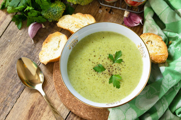 Vegetarian dish. Delicious broccoli cream soup served with garlic croutons on a rustic table. Copy space.