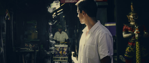 A guy in a white shirt is walking around Bangkok. Authentic quarter in Bangkok. Tourism.	