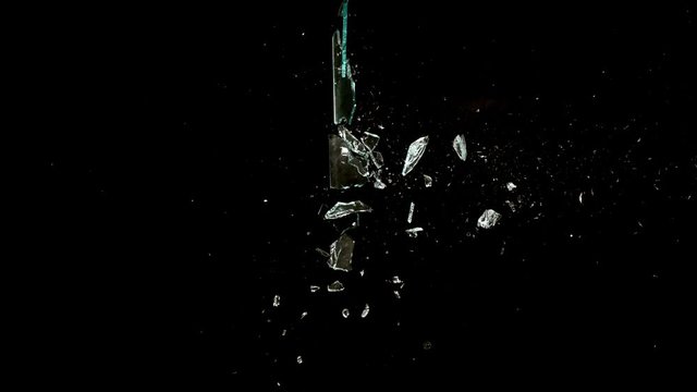 Profile of Glass breaking into fragment spray on black background