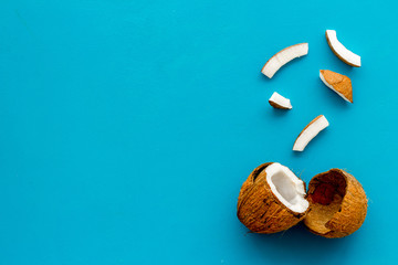 Coconuts frame - halfs and scattered pieces - on blue background top-down copy space