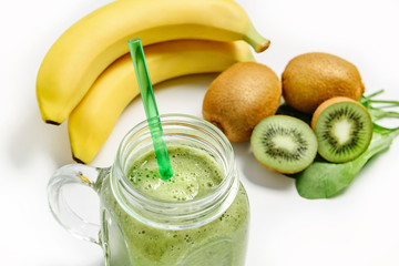 Green smoothie in a glass on a background of kiwi, banana and spinach
