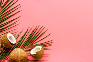 Fototapeta na wymiar Exotic background with coconuts and palm leaves on pink background top-down frame copy space