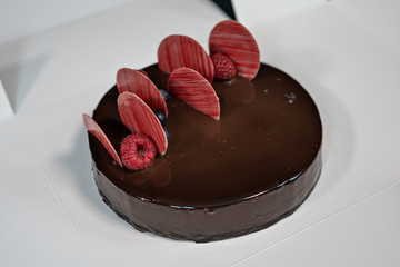 Round glazed chocolate cake with berries on top.