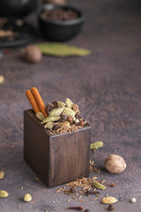 Garam masala, mix of different spices black and white peppercorns, cloves, cinnamon, mace, cardamom, cumin. Indian blend of ground spices in wooden box for cooking and Ayurvedic medicine.