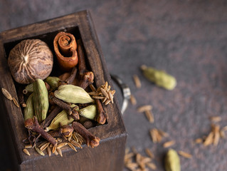 Garam masala, mix of different spices black and white peppercorns, cloves, cinnamon, mace, cardamom, cumin. Indian blend of ground spices in wooden box .Close up