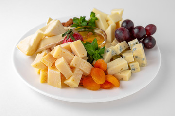 Plate with appetizer of different types of cheese, grapes and nuts with honey. Banquet festive dishes. Gourmet restaurant menu. White background.