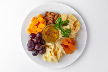 Plate with appetizer of different types of cheese, grapes and nuts with honey. Banquet festive dishes. Gourmet restaurant menu. White background.