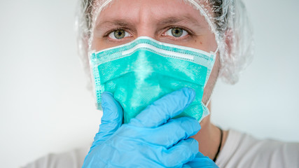Man with blue gloves putting on a medical face mask against Coronavirus Covid-19