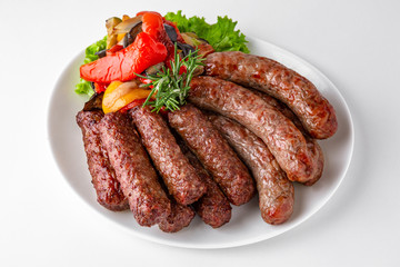 Grilled pork and beef sausages with vegetables. Banquet festive dishes. Gourmet restaurant menu. White background.
