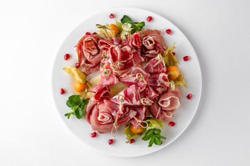 Gentle prosciutto with physalis. Banquet festive dishes. Gourmet restaurant menu. White background.