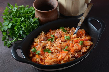 Cabbage stew with grilled sausage in tomato sauce - traditional dish of German, Polish or Russian cuisine