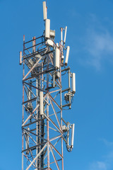 Mobile communication tower close-up against the blue sky, vertical photo