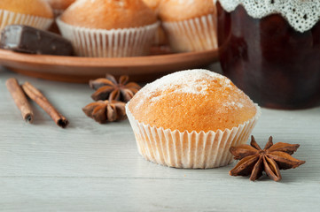 Tasty muffins with icing sugar on a wooden kitchen table ready to eat. Cinnamon sticks and star anise. Sweet dessert.