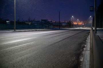 Fototapeta na wymiar Suburban road with lights on a winter snow evening