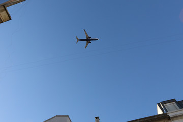 the plane on the background of blue sky flying over the residential area
