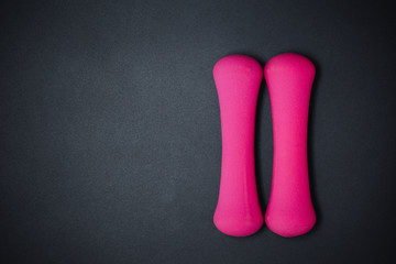 Pink dumbbells on black background, sport and fitness concept.