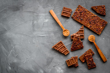 Homemade chocolate. Bars and broken pieces on grey stone table frame copy space