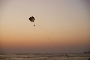 Silhouettes of people with parachute and boat. Evening, sunset. Thailand. Phuket. 