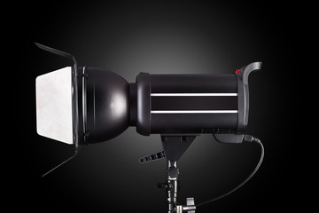 Photography studio flash isolated on black background with lamp.