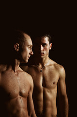 Fototapeta na wymiar Two athletic wet guys. Love. Black background.