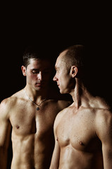 Fototapeta na wymiar Two attractive wet guys. Black background.
