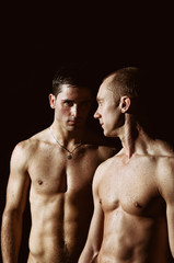 Two athletic wet guys. Love. Black background.