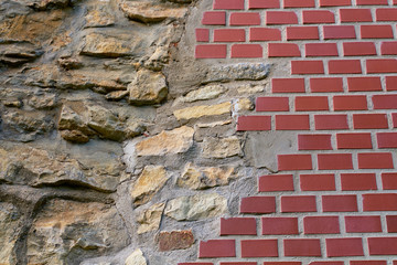 Repair of an old stone wall to a new red brick wall. Beautiful interesting interactive texture. Section of the new and old.