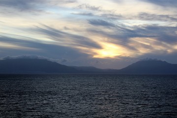 Fototapeta premium evocative image of sunset over the sea with headland silhouette in the background