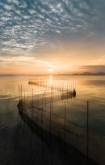 Sunset landscape with a row of fishing nets on the sea
