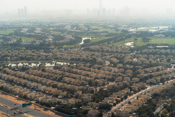 Fototapeta na wymiar Aerial view of Dubai with villas and houses of local residents on foreground and high-rise skyscrapers buildings in morning dusk on background, United Arab Emirates.