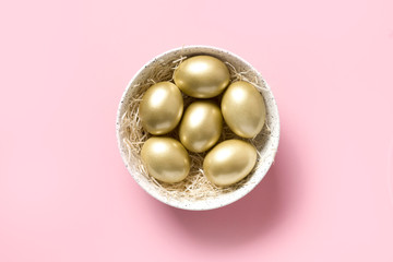 Easter golden chicken eggs in bowl on pink. View from above.