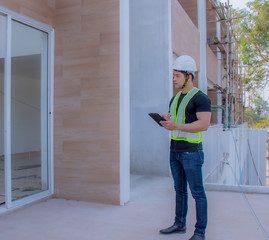 The foreman wearing a white helmet stood on a tablet in the construction site.	