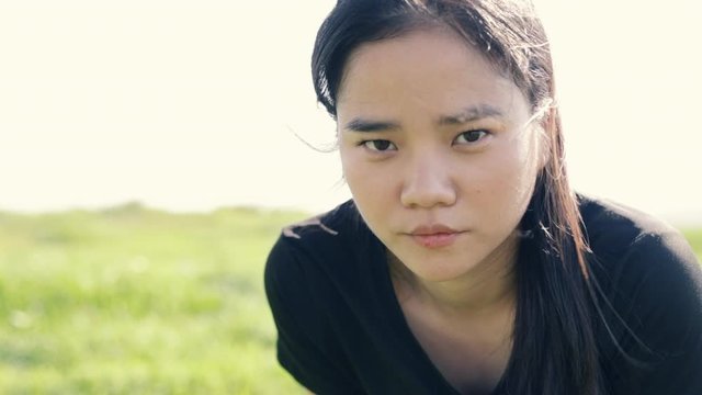Close up face Asian female athlete runner resting exhausted look at the camera after a cardio workout exercise. Fitness and a healthy lifestyle.