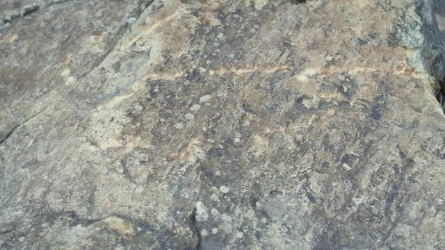 The hand touches the rough surface of the stone