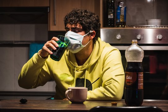 Man with a mask tries to drink while protecting to coronavirus COVID-19 due to hysteria and panic caused by media and governments a very contagious virus