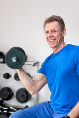 Fototapeta na wymiar Mature smiling man doing work out in a fitness room