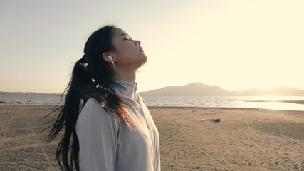 Young asian woman runner relaxing on the beach while beautiful sunset. Athlete wellness cardio lifestyle.