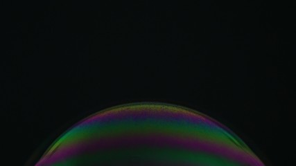 Rainbow soap bubble on a dark background. Close-up of colorful surface