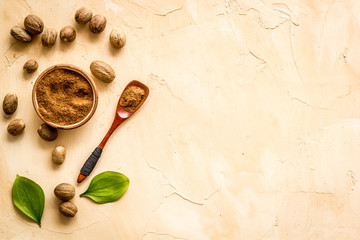Nutmeg - ground indian condiment in spoon - on beige background top-down copy space