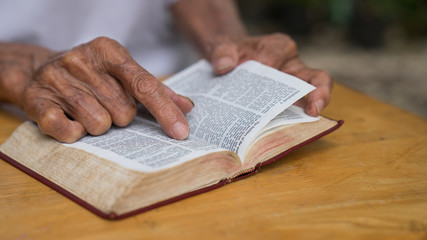 Naklejka premium Old man reading her bible while sitting outside