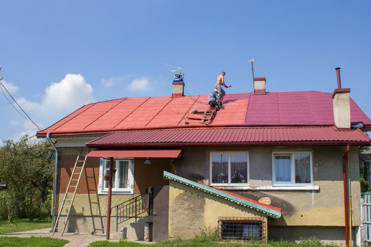 father with son paint the roof,son helps his father paint the roof at home