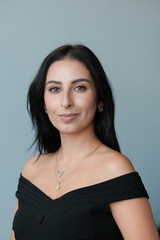 Obraz premium A large portrait of a middle-aged woman (30-35 years old) with dark hair and brown eyes in a black dress on a light background.