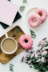 Composition of flowers, coffee and donuts on a white background, flat top view