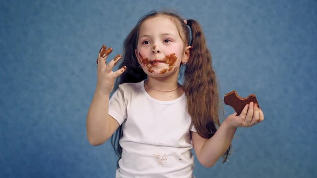 Girl with chocolate plate. Little girl eating chocolate plate on table