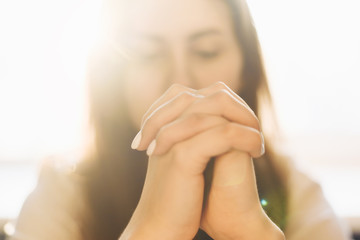 Cute beautiful girl folded her hands in prayer. A woman asks God for help - obrazy, fototapety, plakaty