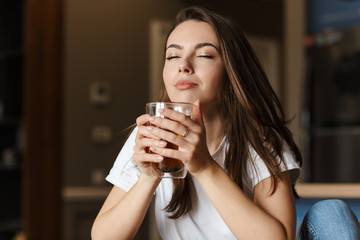 Image of pleased beautiful woman drinking tea with eyes closed