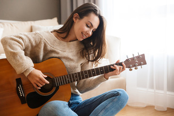Image of happy beautiful woman playing guitar and composing song - Powered by Adobe