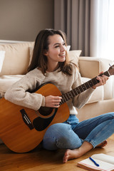 Image of happy beautiful woman playing guitar and composing song