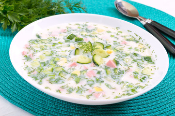 Cold summer soup okroshka. Light soup in a white bowl.