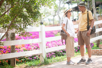 Asian old couple traveler enjoy happy time together while sightseeing in flower garden or public park in  summer time. Healthy and positive retirement people lifestyle